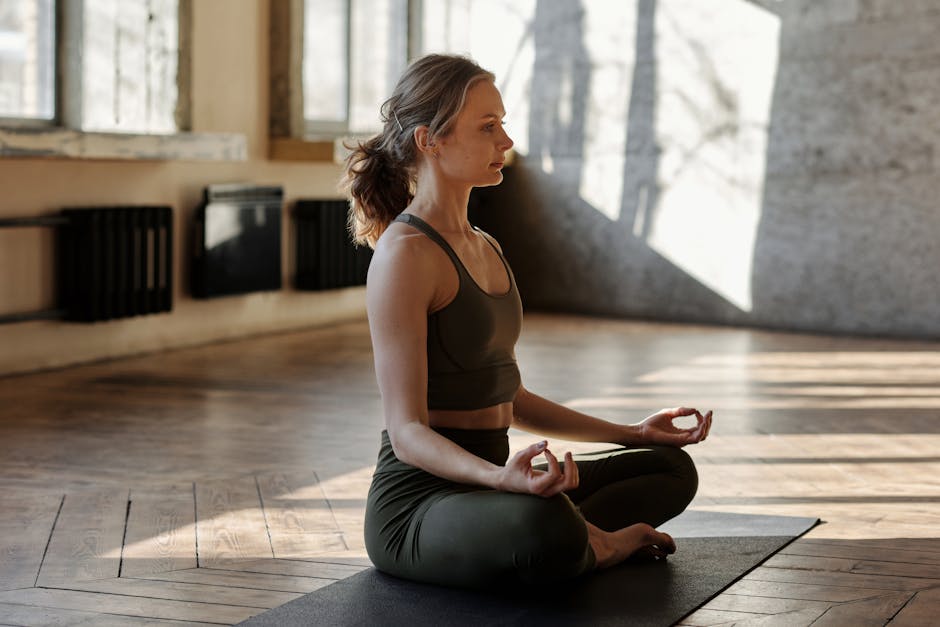 A woman meditating with a peaceful smile, sitting cross-legged indoors